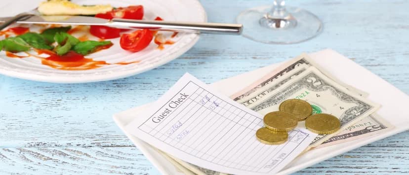 Restaurant receipt, coins and leftover food on a table