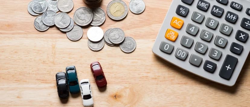 Coins, a calculator and toy cars arranged on a desk