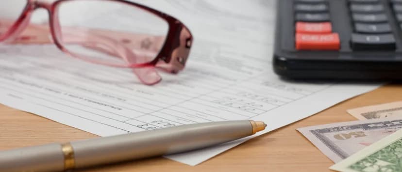 Calculator, pen and financial document on a desk