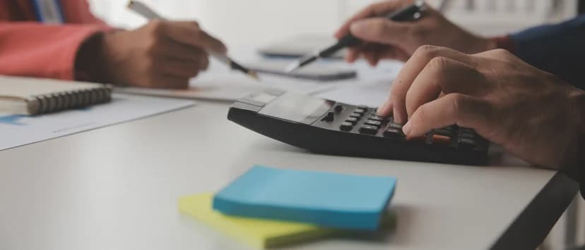 Person calculating financial figures on a laptop