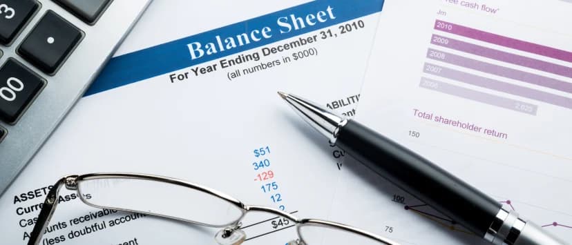 Calculator, glasses and pen on a financial report with charts