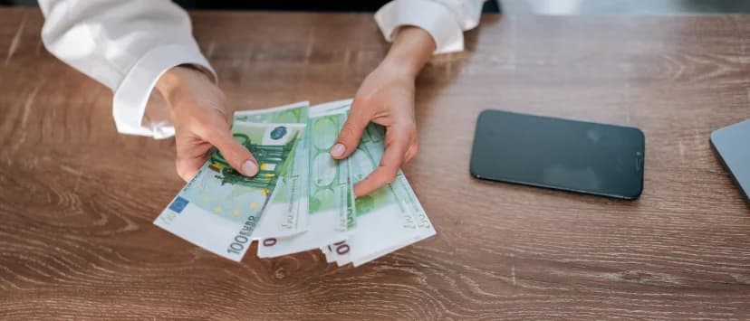 Persoană care numără bancnote euro la birou