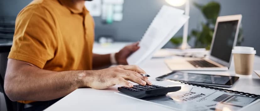 Persoană care verifică acte financiare cu un calculator de birou