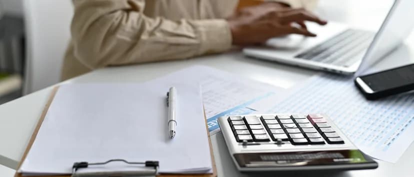 Calculator și documente salariale pe biroul unei persoane care lucrează la laptop